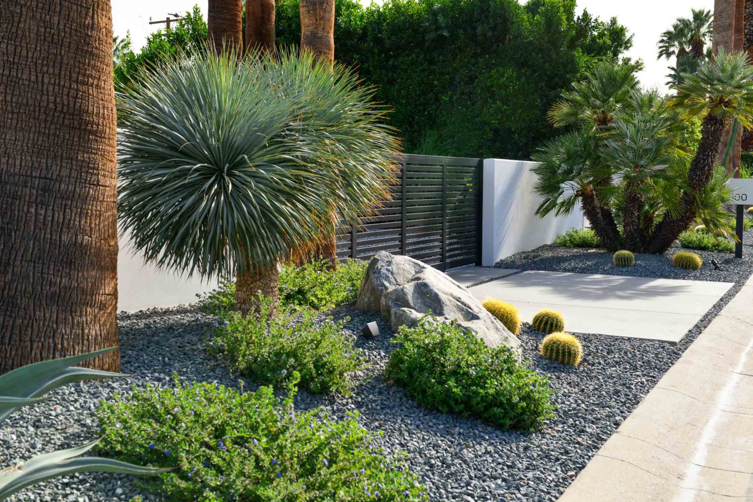 Complete landscape transformation in Palm Springs. Installation includes acid washed hardscape layout, outdoor living area with pizza oven, BBQ, Fireplace, Outdoor shower with breeze block, low voltage lighting, boulders, irrigation and desert plants. Design also includes new driveway automatic gate and new pedestrian entry gate and new garden walls in front yard.